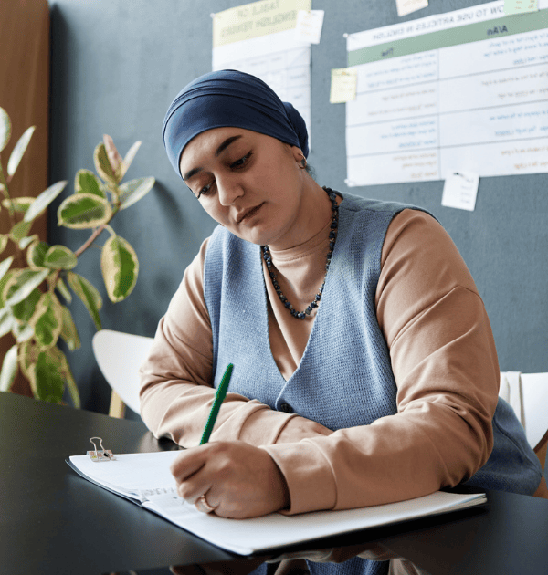 Female teacher Writing in Notebook Sitting at Desk during her cpd training