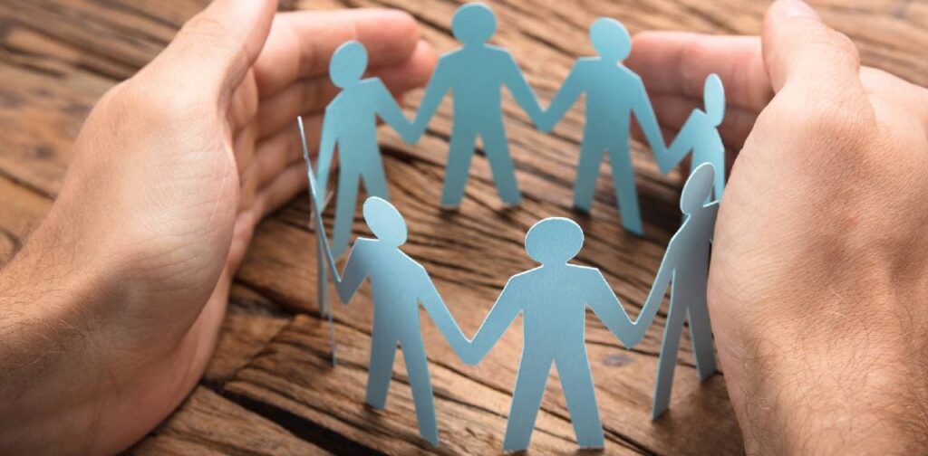 Businessman's Hands Covering Paper Team On Table indicating safeguarding training