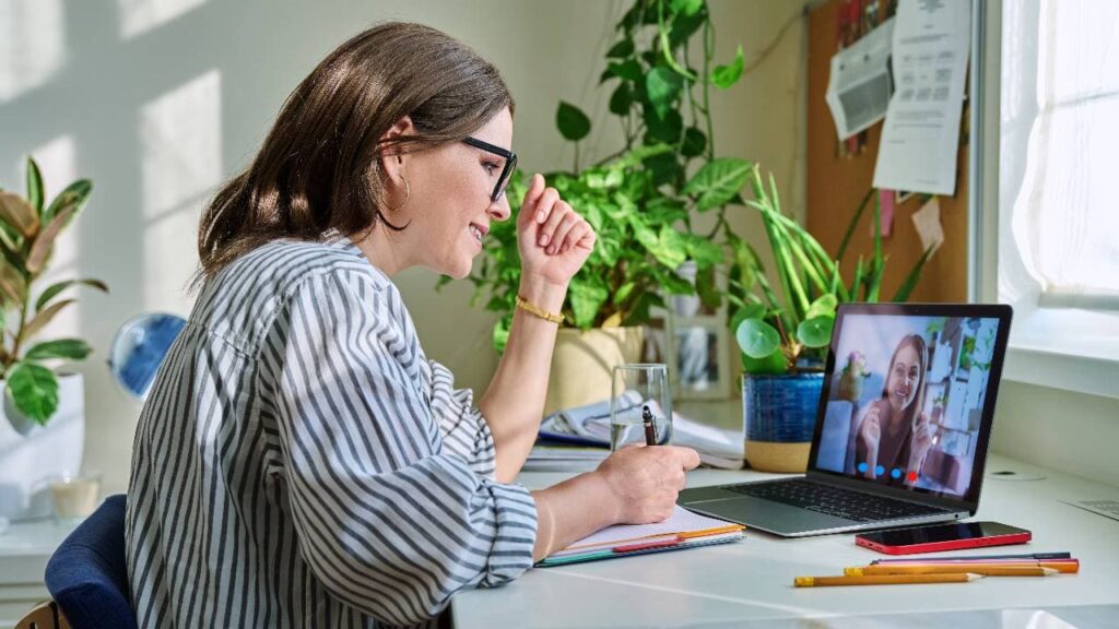 Middle aged female teacher having video conference on laptop with young woman