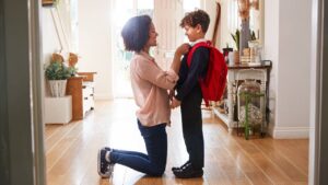 Mother At Home Getting Son Wearing Uniform Ready For First Day Of School