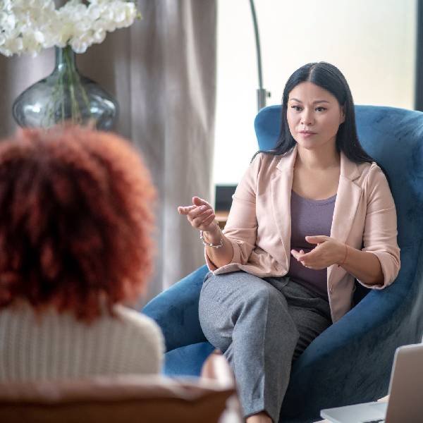 Asian professional female senior mental health lead speaking with school colleague about their mental health