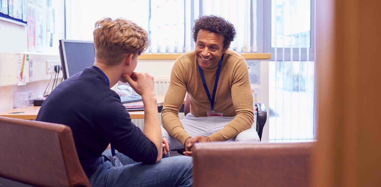 Male Sixth Form Student Meeting With Male School Mental Health Lead Discussing Mental Health Issues